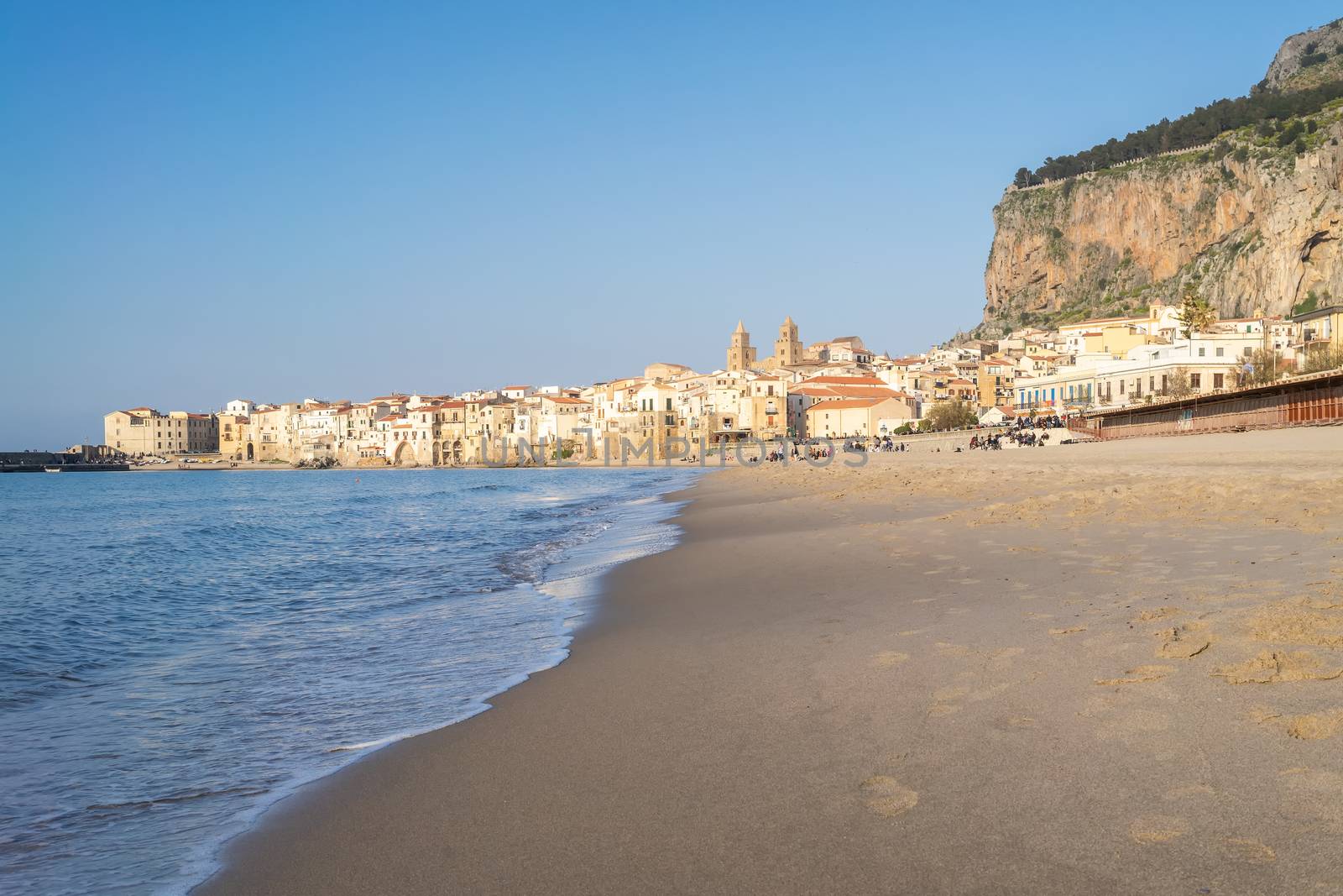 Idyllic view of Cefalu from the long sandy beach. Cathedral and Rocca di Cefalu rocky mountain on a sunny day in Cefalu, Sicily, Southern Italy. by tamas_gabor