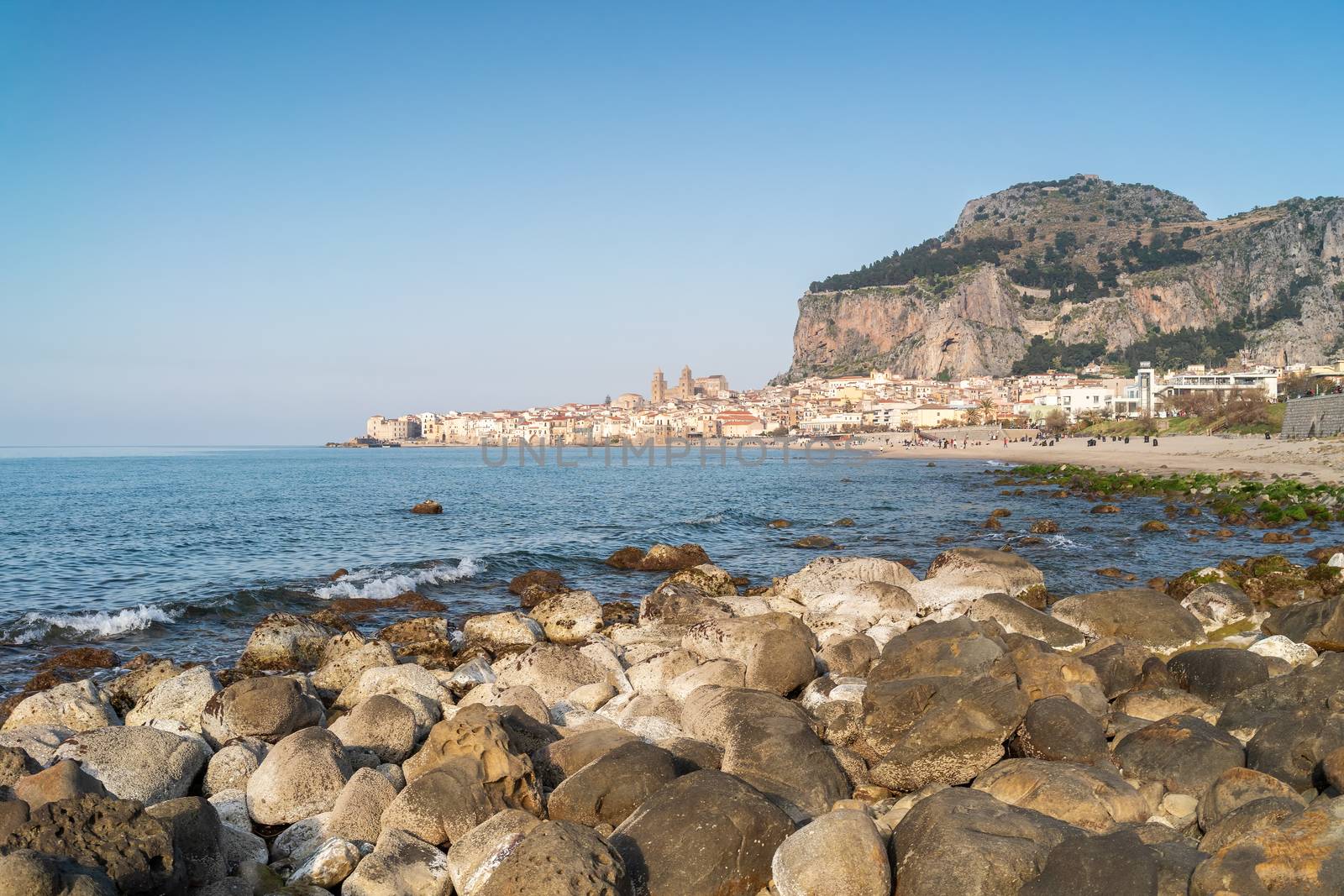 Idyllic view of Cefalu from the long sandy beach. Cathedral and Rocca di Cefalu rocky mountain on a sunny day in Cefalu, Sicily, Southern Italy. by tamas_gabor