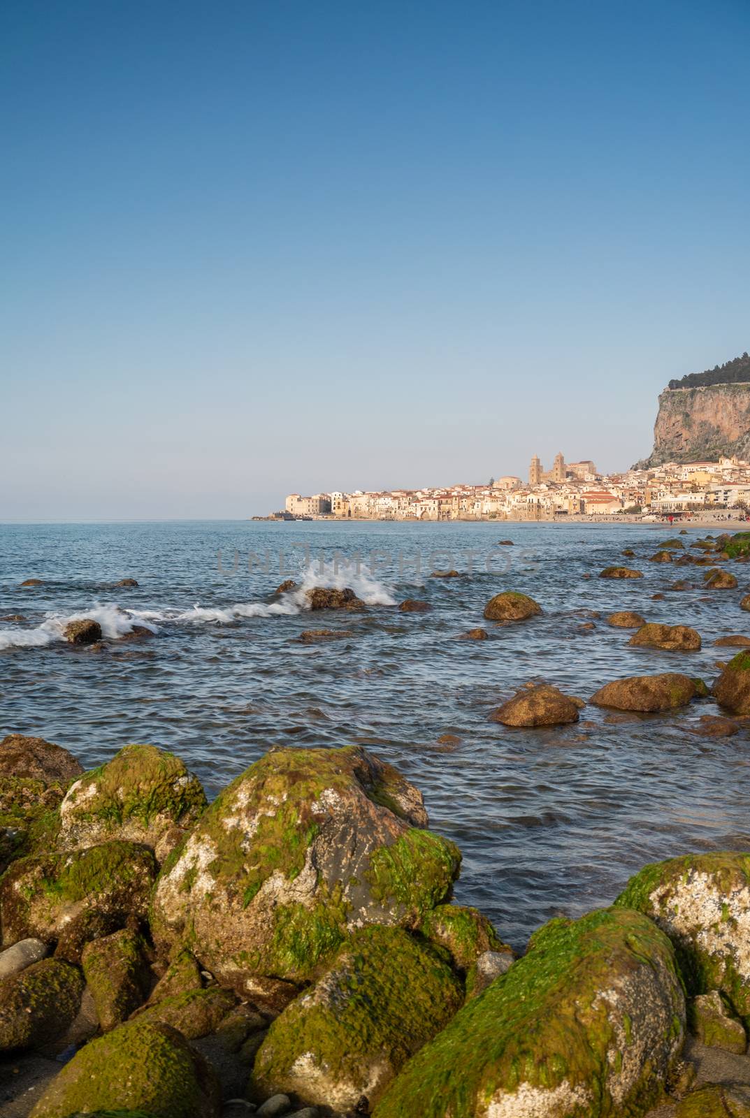 Idyllic view of Cefalu from the long sandy beach. Cathedral and Rocca di Cefalu rocky mountain on a sunny day in Cefalu, Sicily, Southern Italy. by tamas_gabor