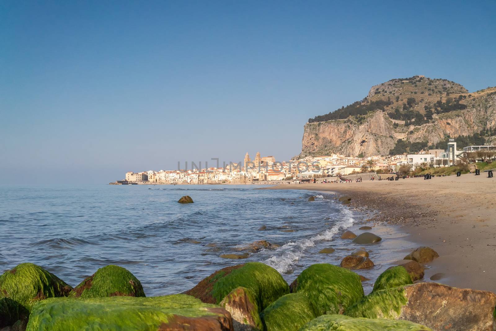 Idyllic view of Cefalu from the long sandy beach. Cathedral and Rocca di Cefalu rocky mountain on a sunny day in Cefalu, Sicily, Southern Italy. by tamas_gabor