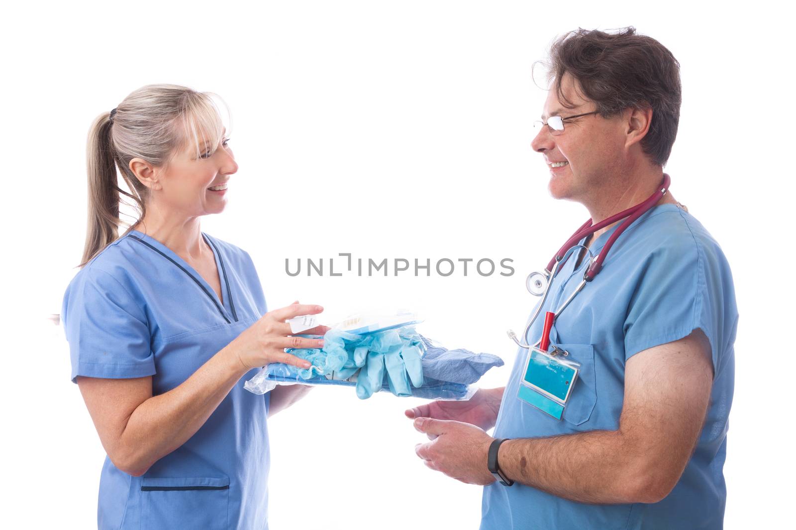 Hospital staff hands a PPE kit consisting of cull body coverall, N95 respirator mask, gloves, hair cover and foot covers to another nurse or doctor