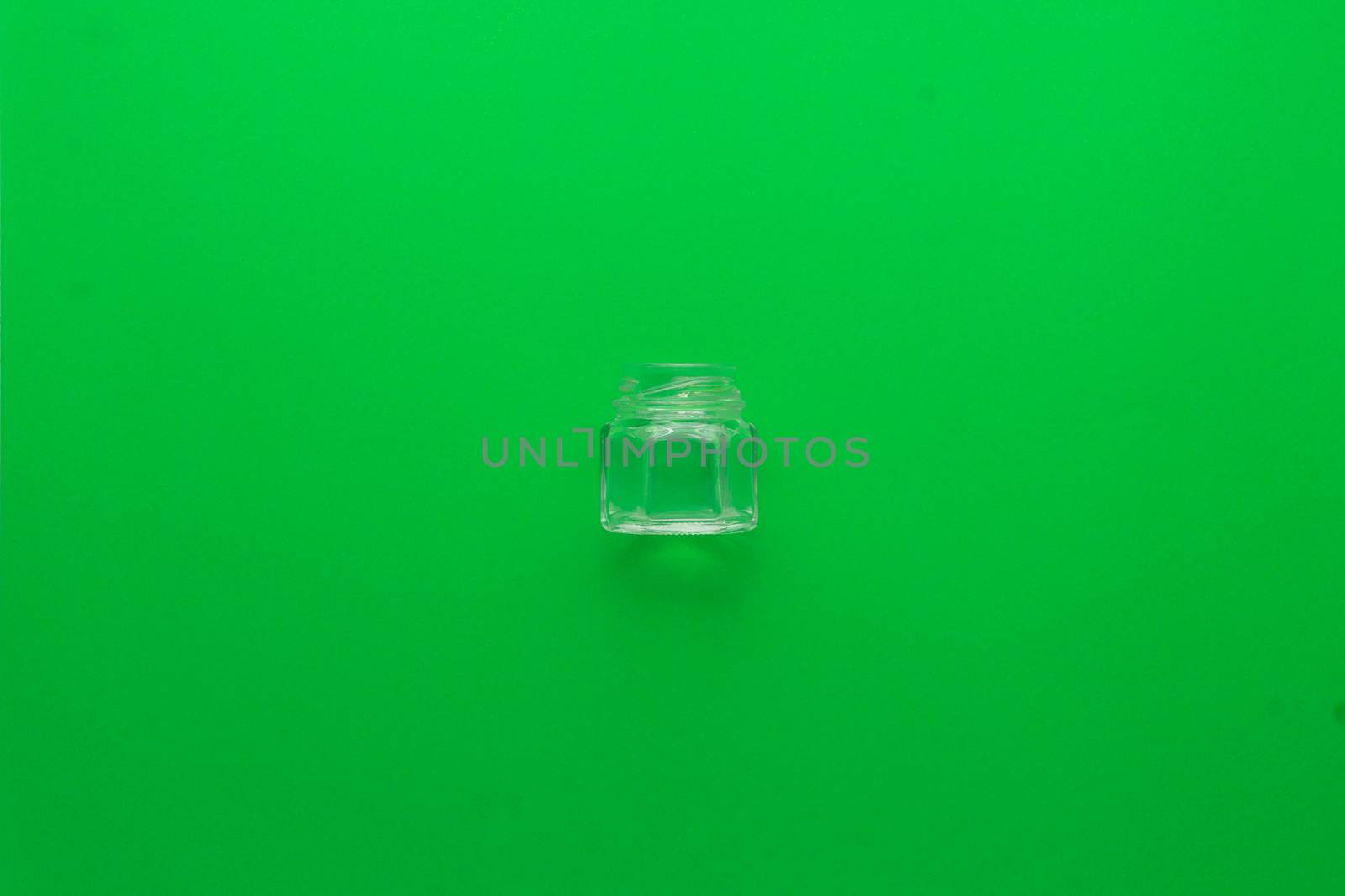 Small glass pot on a green background located in the center. Recycling glass to the green container