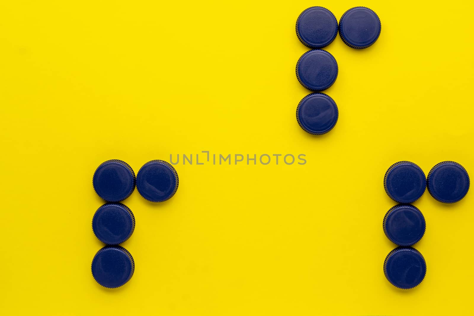 Concept of the three R's: recycle, reuse, reduce. Plastic bottle caps on a yellow background