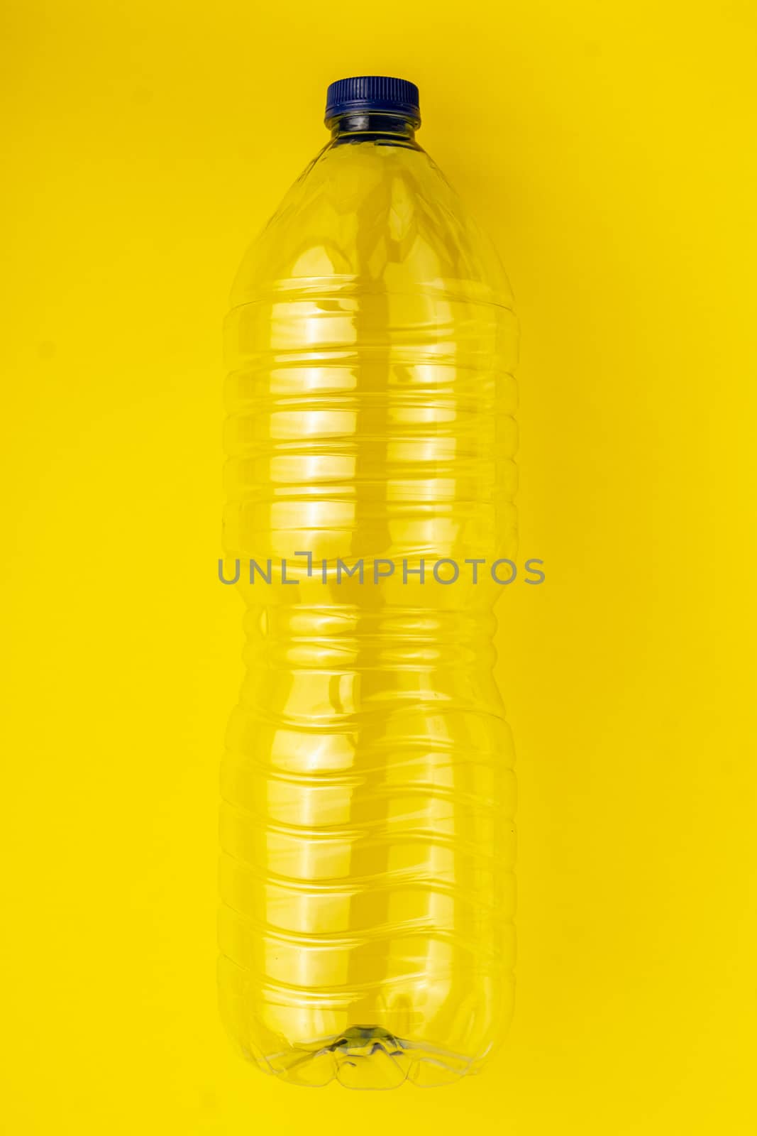 Empty plastic bottle of water on a yellow background. Concept of collecting garbage to the yellow container