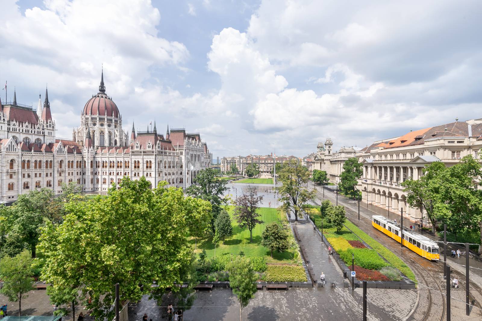 Hungarian parliament building from behind and yellow vintage tram passing by on a sunny day in summer season in Budapest, Hungary - aerial view. by tamas_gabor