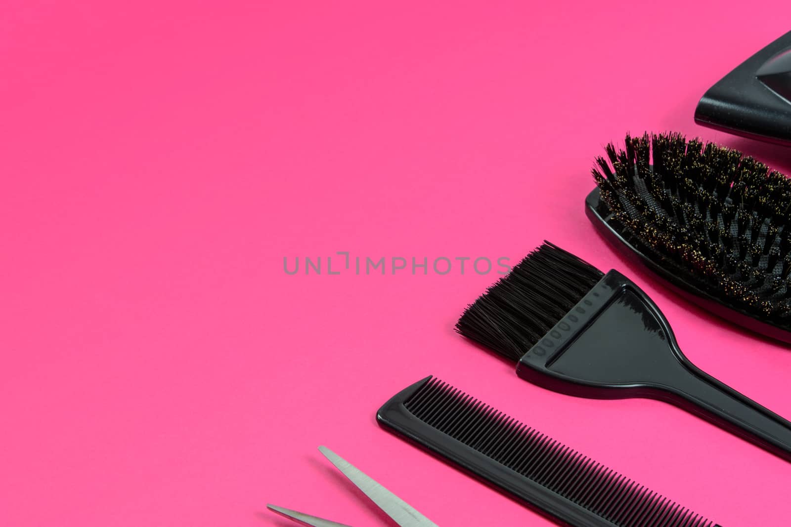 Hairdresser set with various accessories on a pink background with copy space