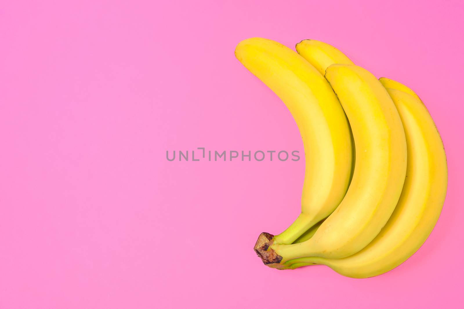 Funny concept image - bunch of bananas isolated on a pink background in top view (copy space)