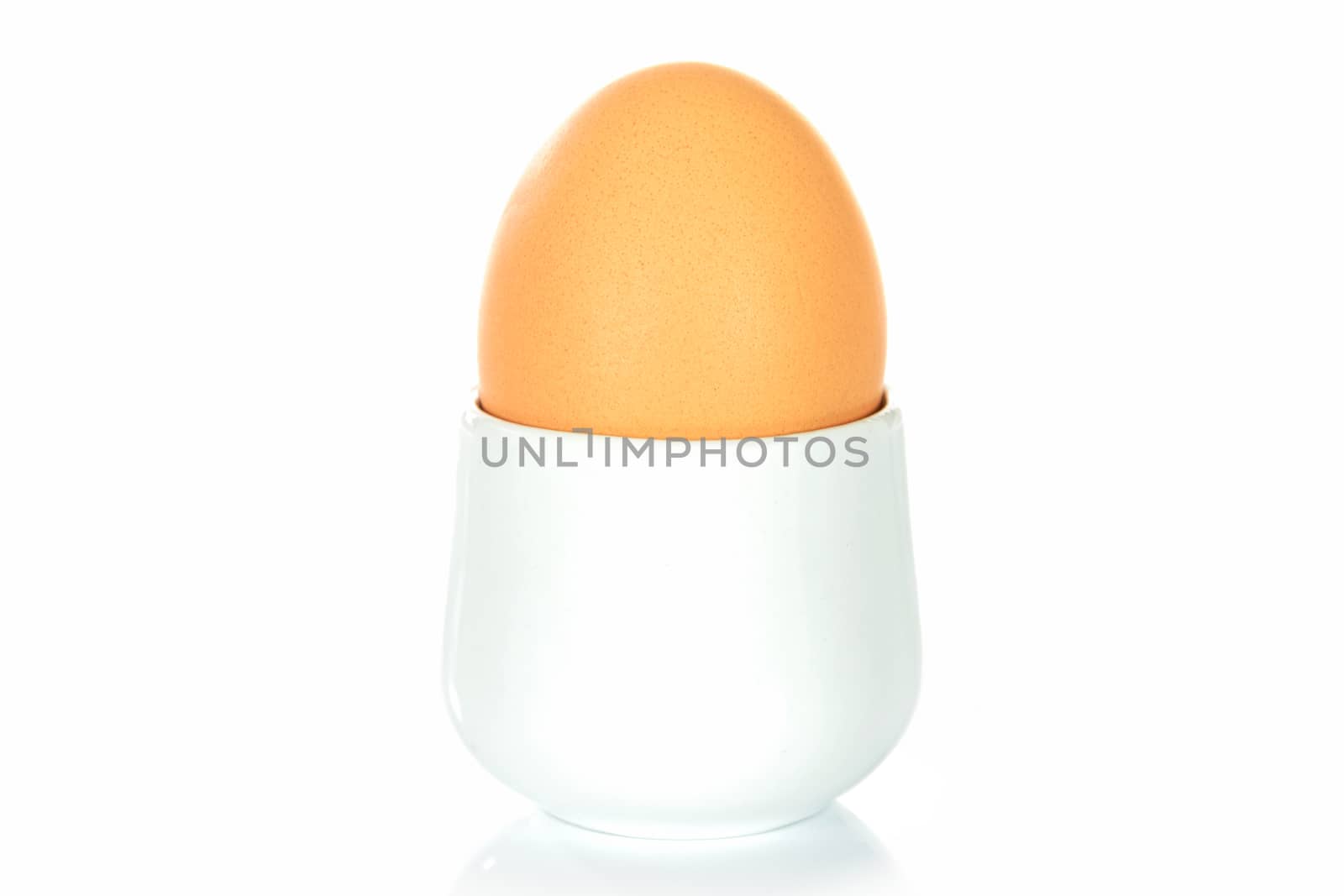 Boiled egg in an egg cup on a white background.