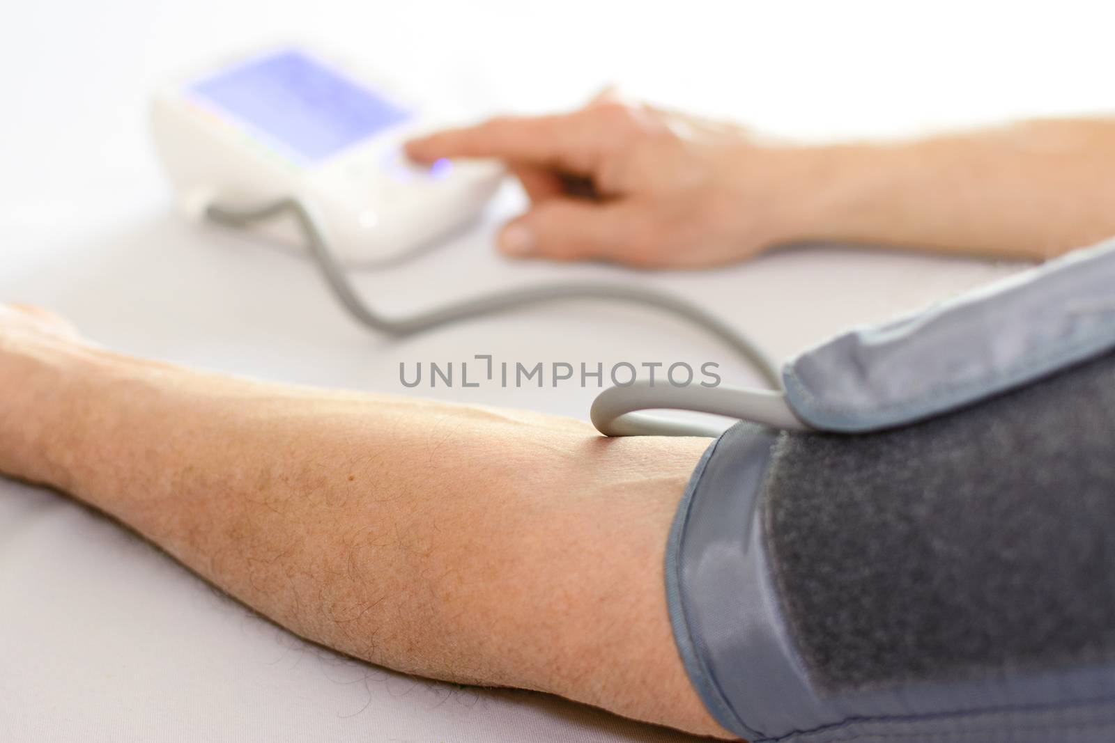 Health care and medical concept - senior man checking his arterial blood pressure with digital home meter in close-up (selective DOF)