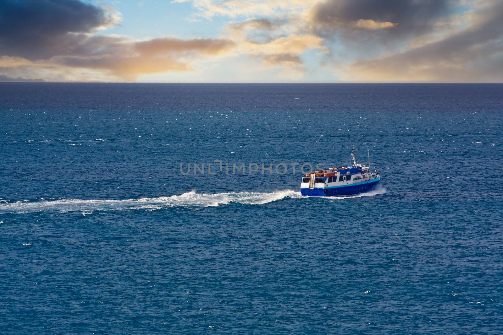 A blue ferry boat cruising across a blue bay