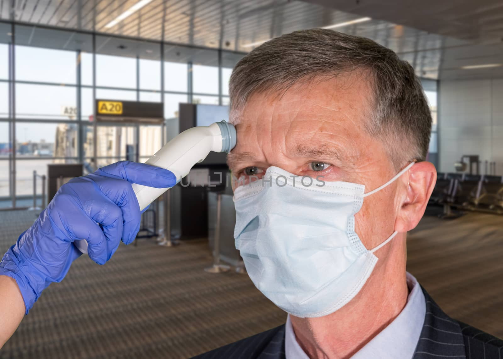 Senior man wearing face mask having temperature taken to check for virus at airport by steheap