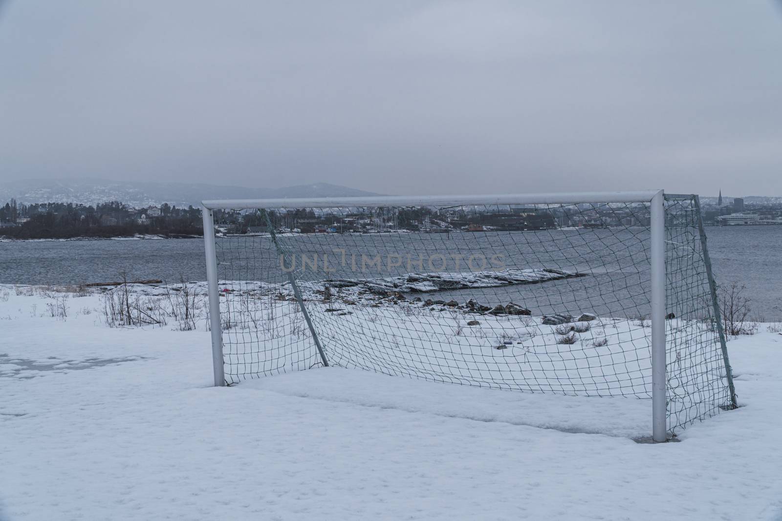 Old soccer goal in a snowy field close to a river in a fjord in Oslo, Norway