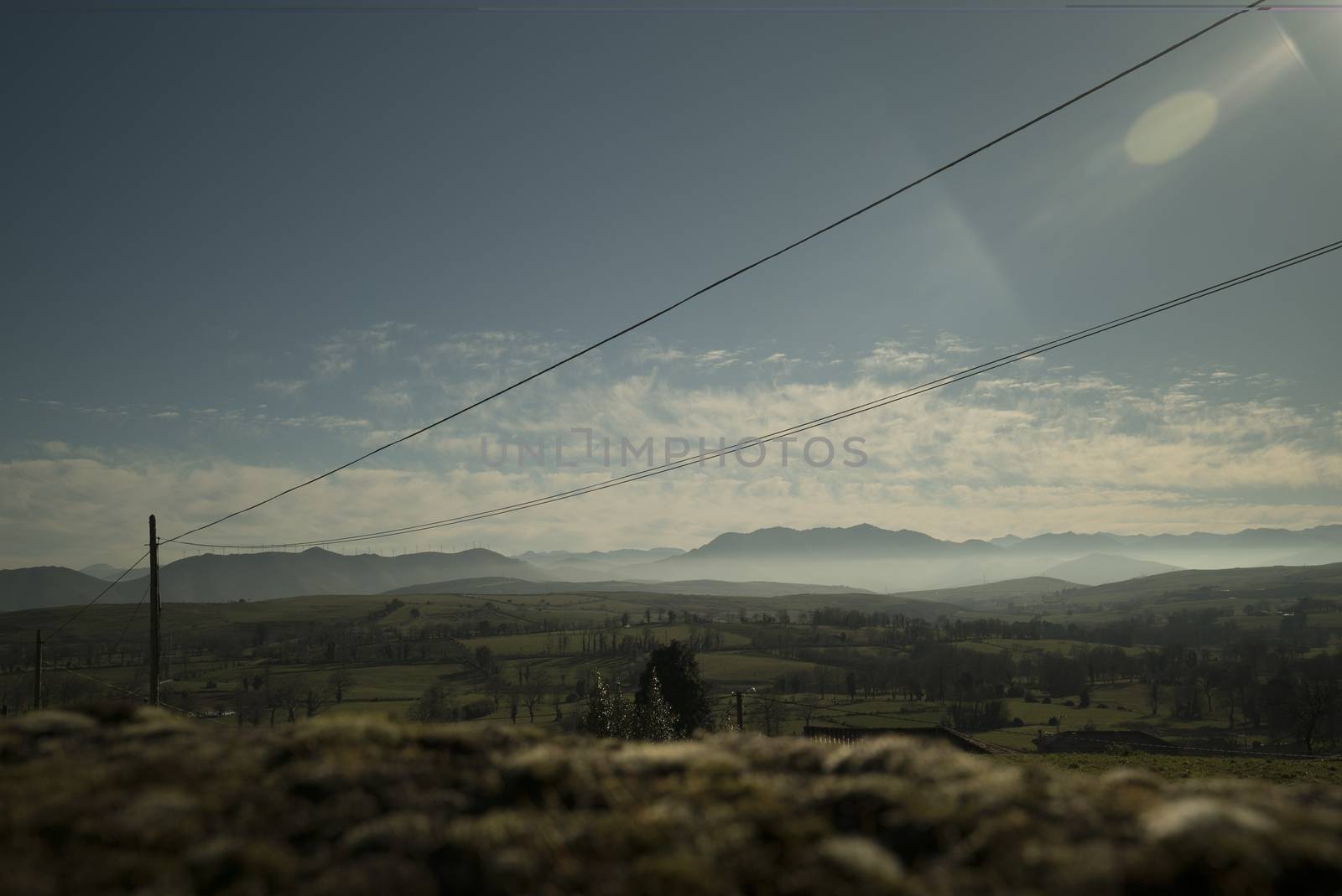 Beautiful landscape of grasslands fields with cable posts and mountains in sunny day
