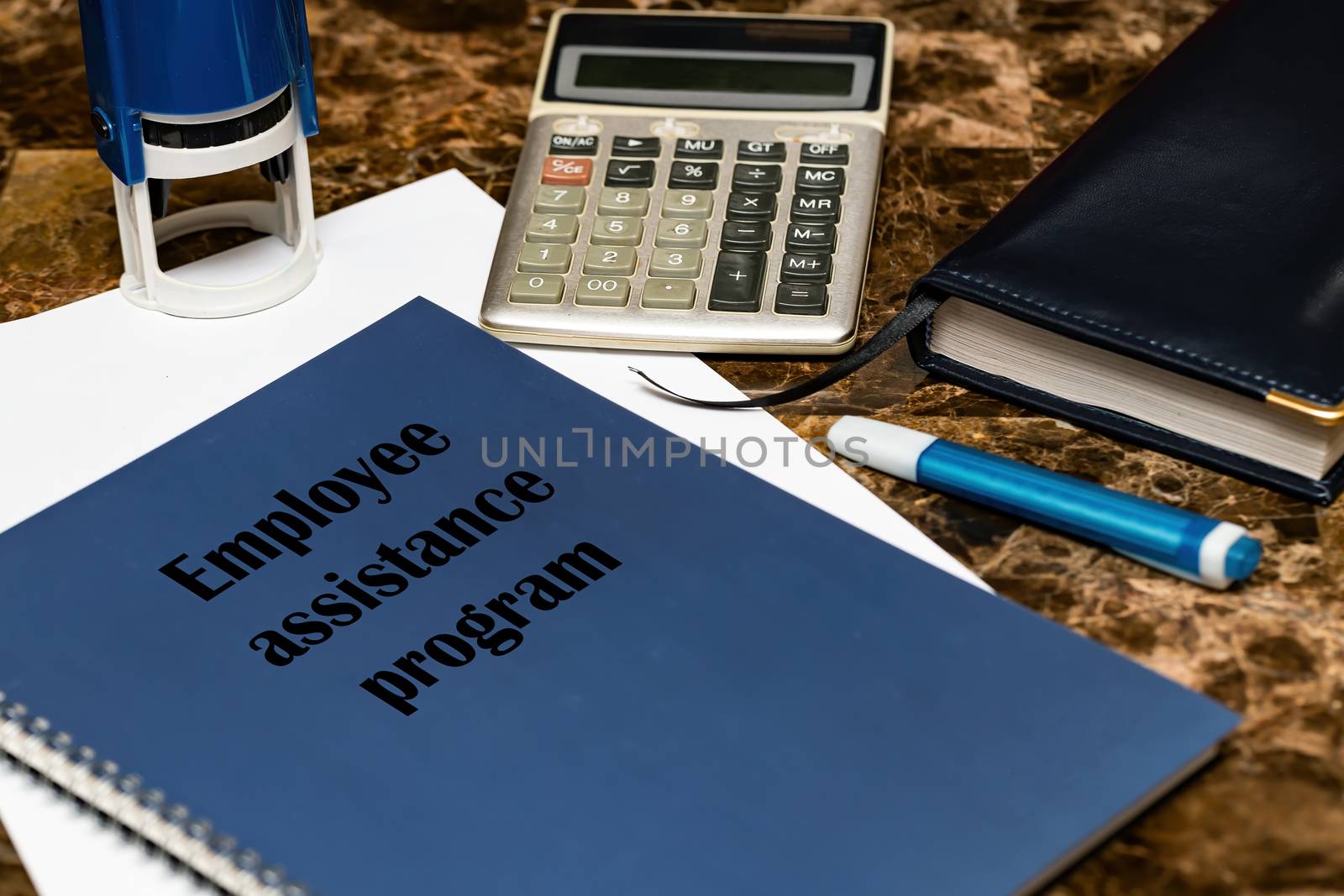 The EAP employee assistance program is written on a blue book lying on a marble Desk in the office among papers