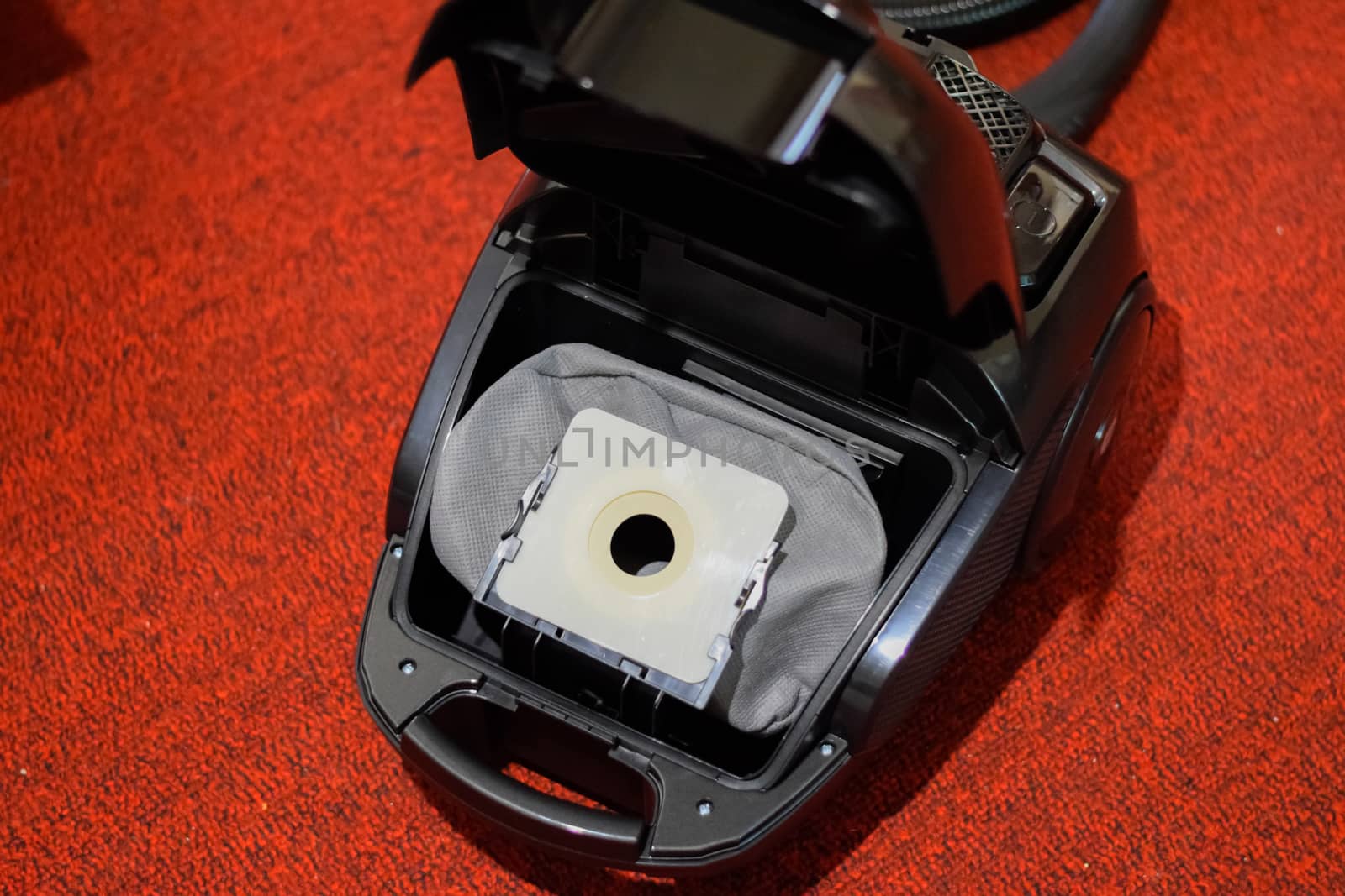 A vacuum cleaner with a set of brushes and bags. A vacuum cleaner on the red carpet.