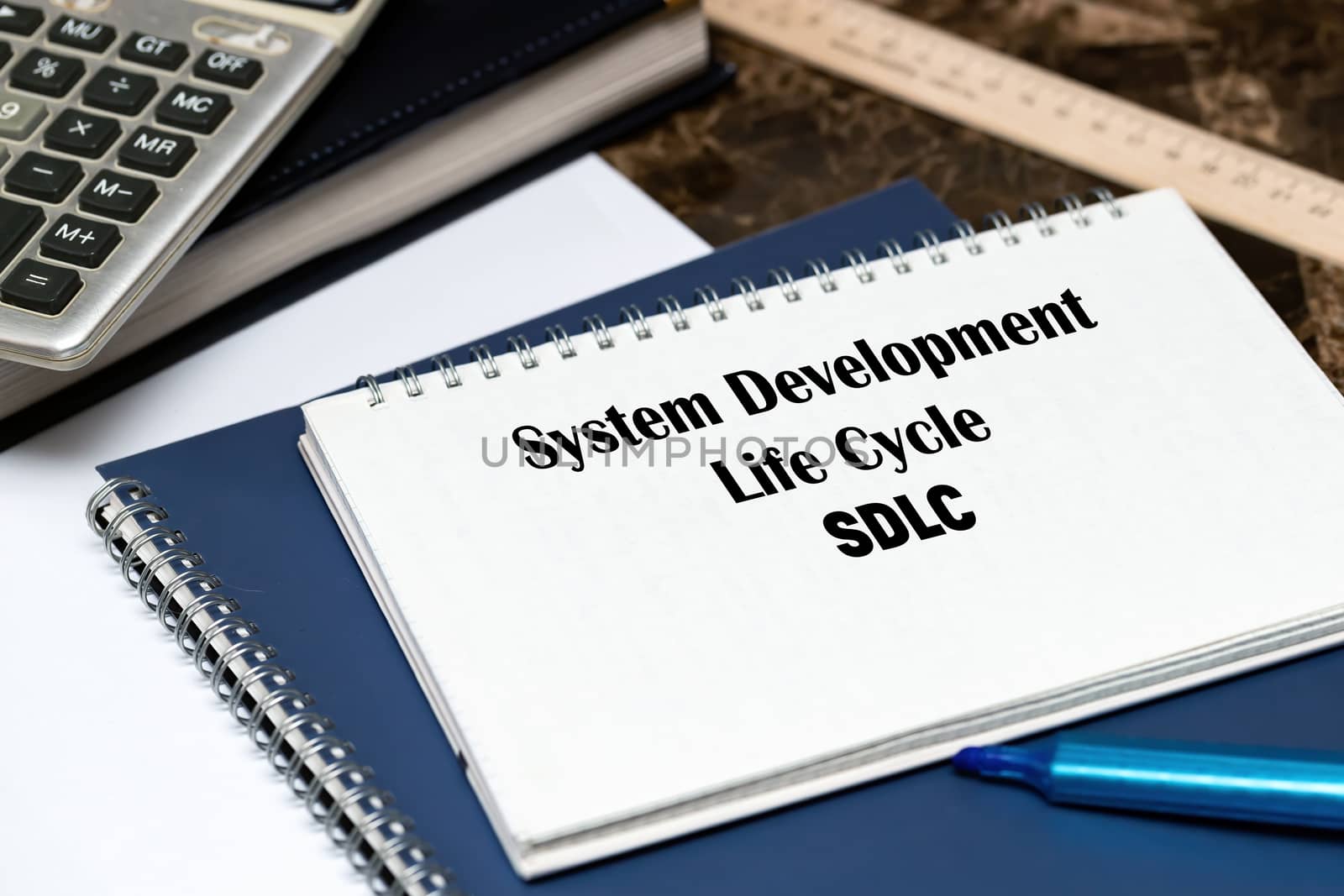 SDLC - System Development Life Cycle, acronym business concept. The text is written on a white sheet that lies on the office marble table.