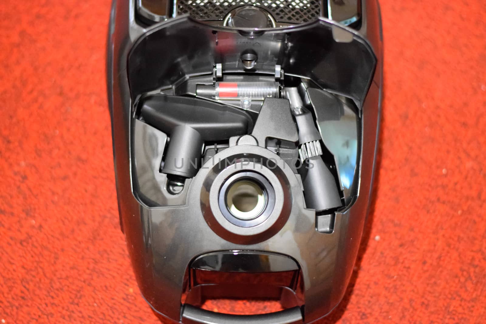 A vacuum cleaner with a set of brushes and bags. A vacuum cleaner on the red carpet.