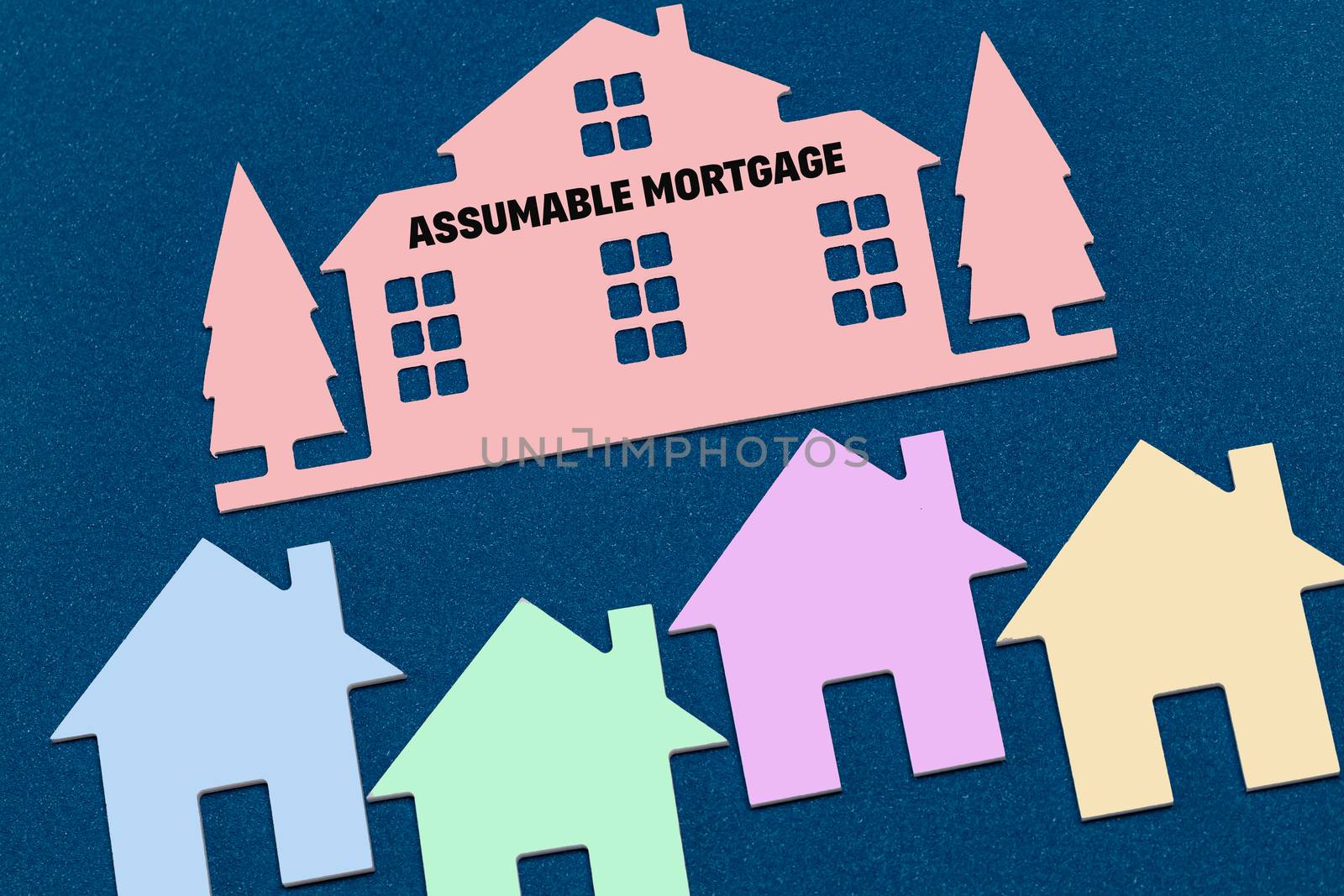 Colorful toy houses on a blue background. Text Assumable mortgage. The concept of profitable investment in real estate.