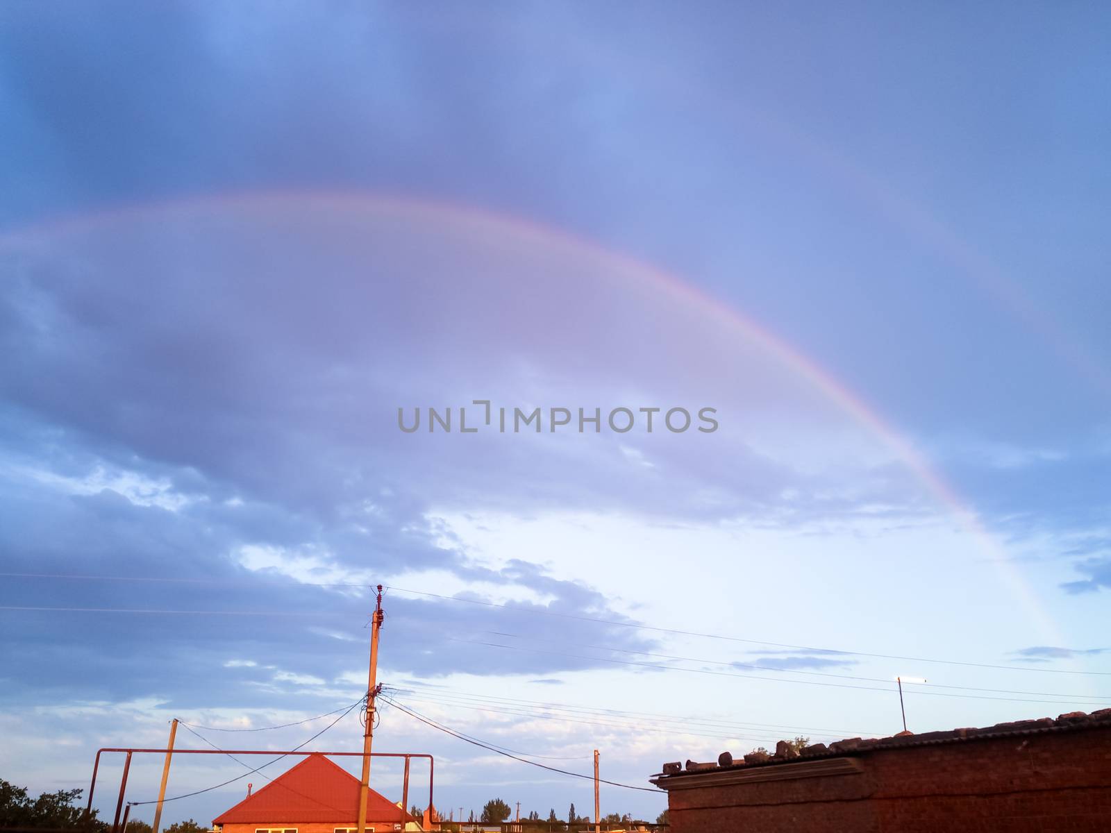 Rainbow over the village. Rainbow after rain.
