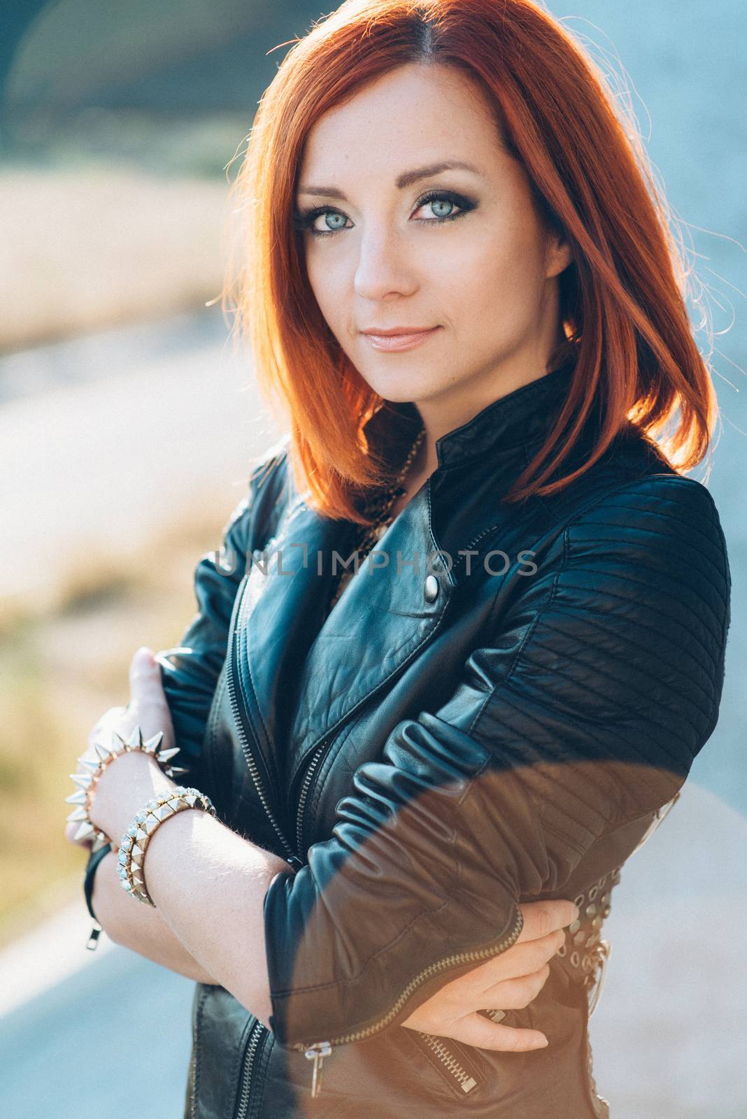 red-haired girl in a black jacket and blue glasses on a gray road