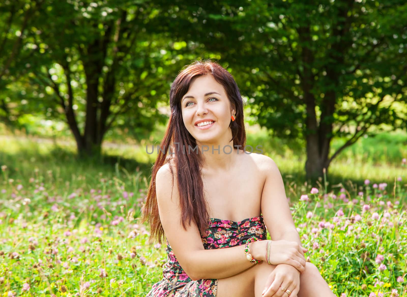 young beautiful smiling girl sitting on the grass by raddnatt