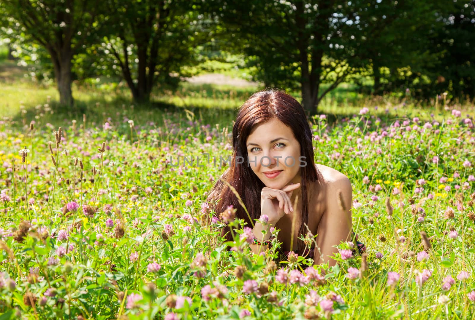 portrait of young pretty woman lying on the grass in the park on sunny summer day closeup