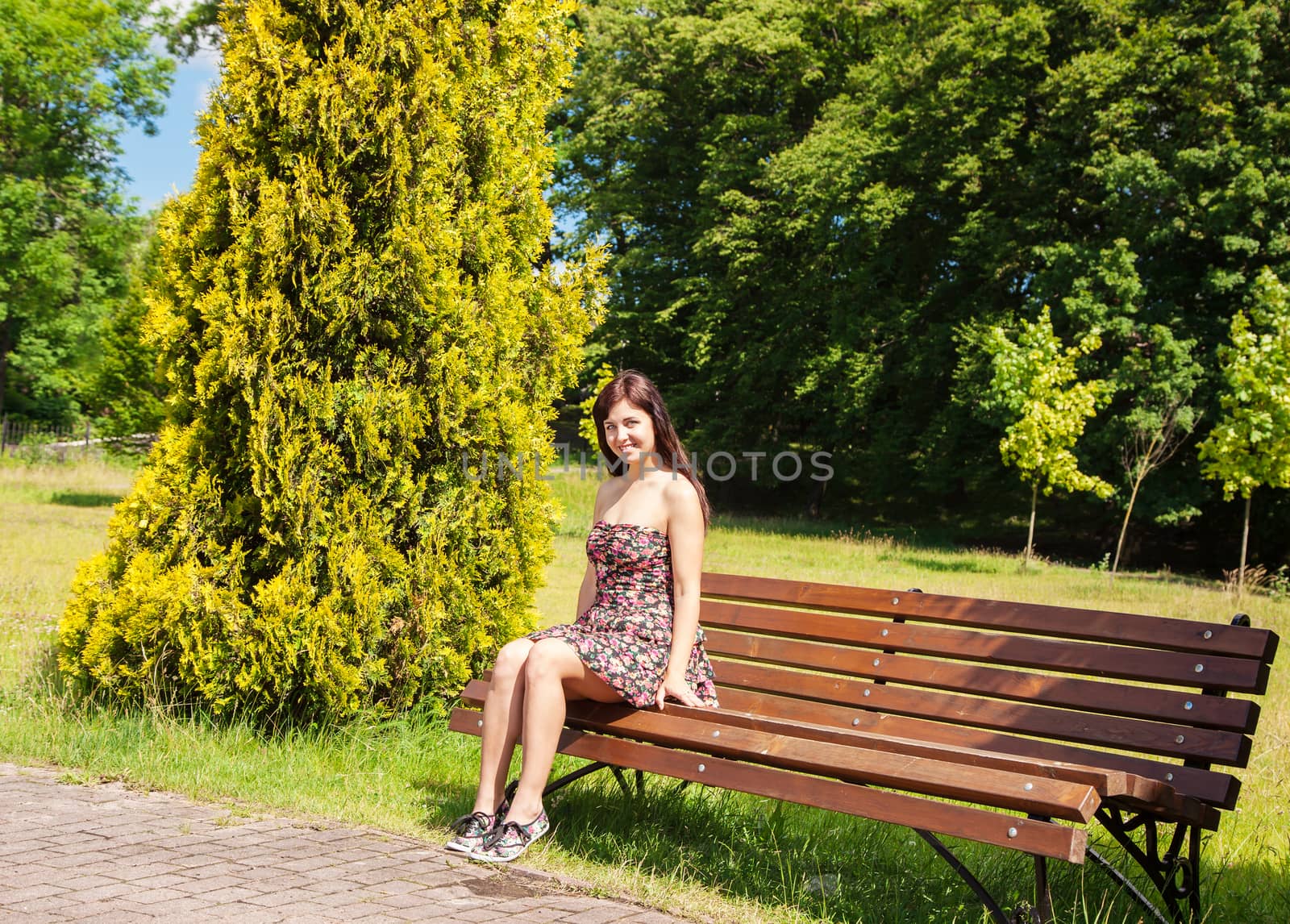 young woman sitting on a park bench by raddnatt