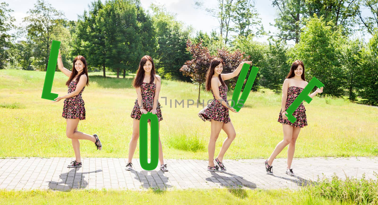 four young pretty smiling girls holding letters with the word love outdoor on sunny summer day