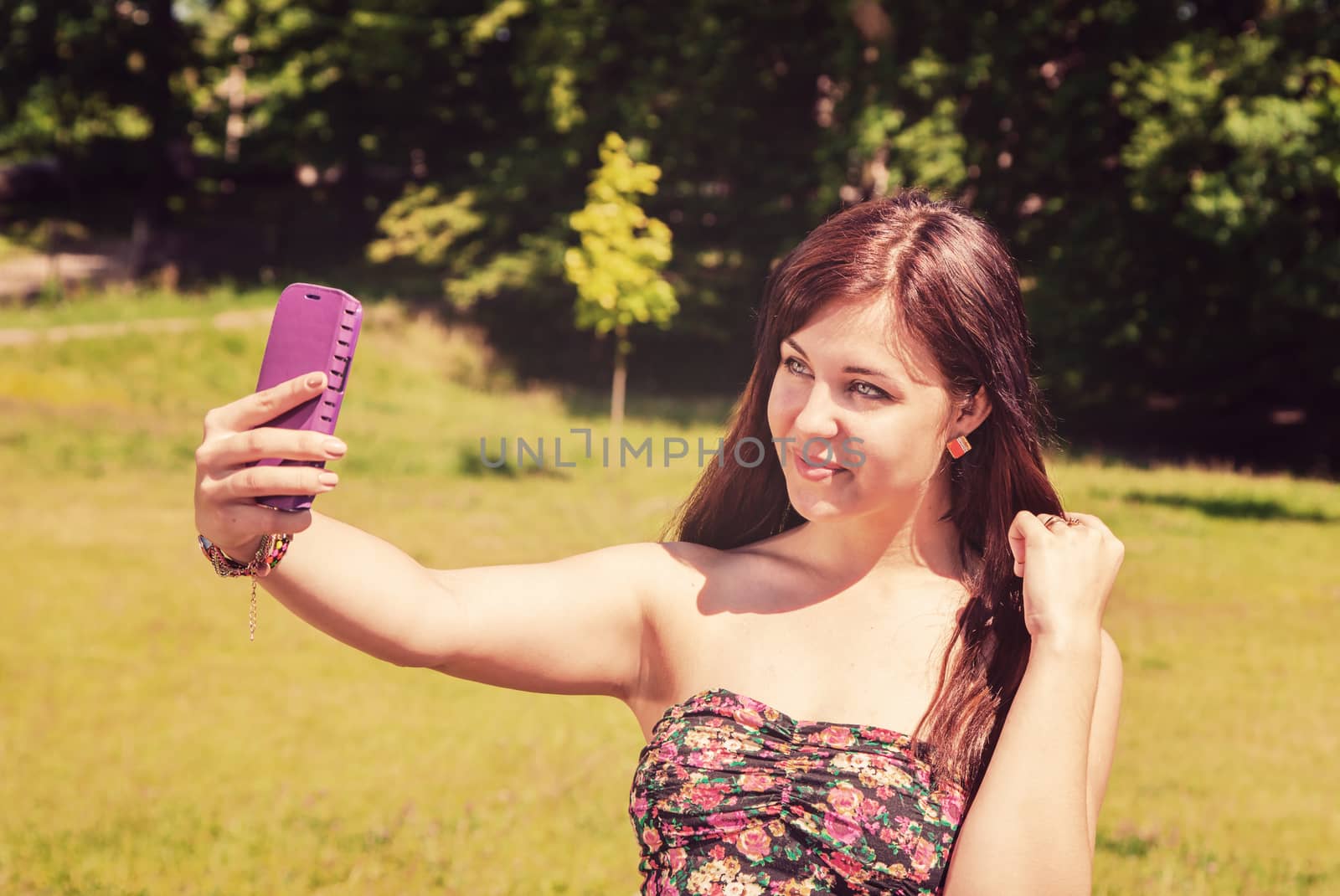 young beautiful girl making selfie in a park on summer day