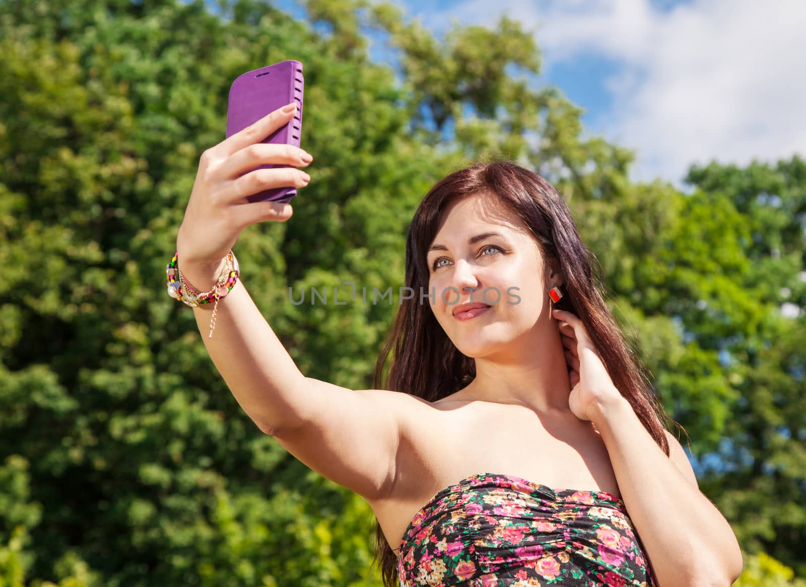 young beautiful girl making selfie in a park on summer day closeup