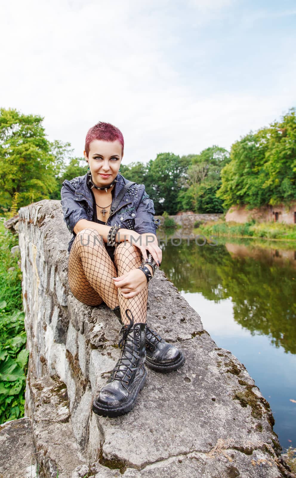 punk girl sitting on the dike near the lake outdoor
