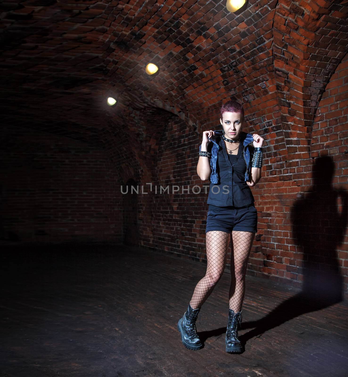 punk girl standing in the dark corridor of hte abandoned castle