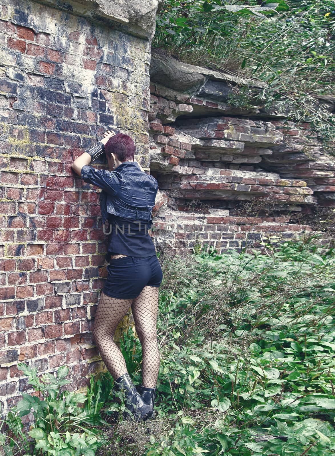 punk girl standing near the wall of hte abandoned castle outdoor