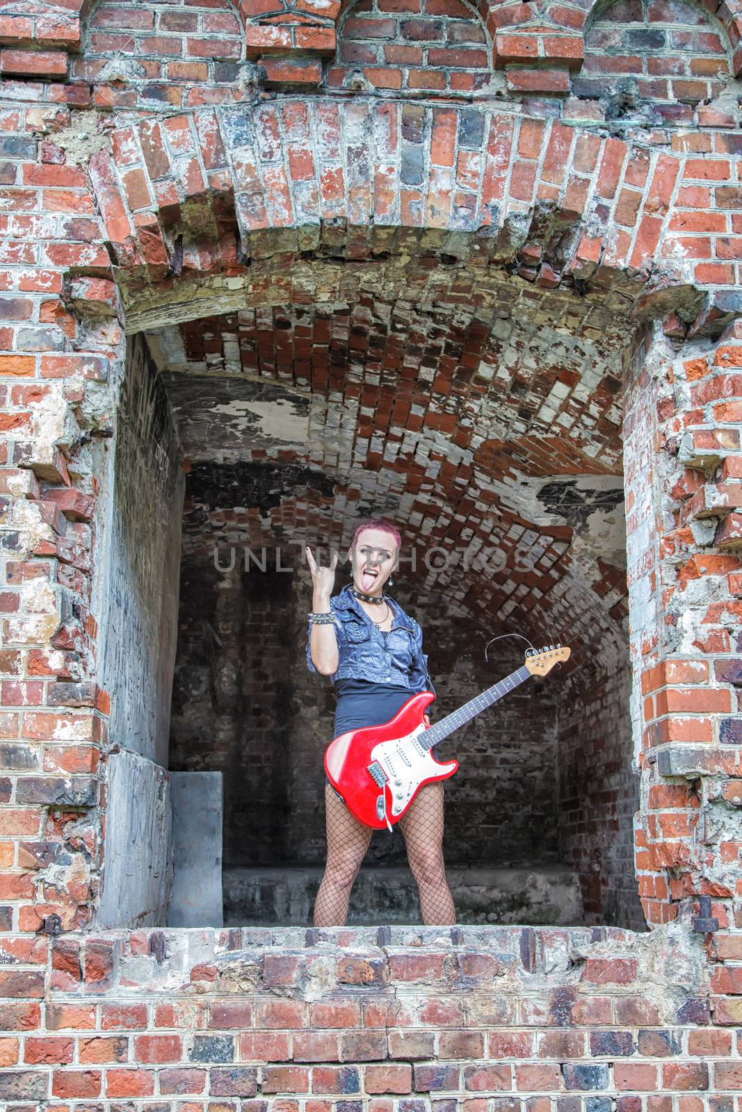 punk girl with red electric guitar standing in the window of hte abandoned castle
