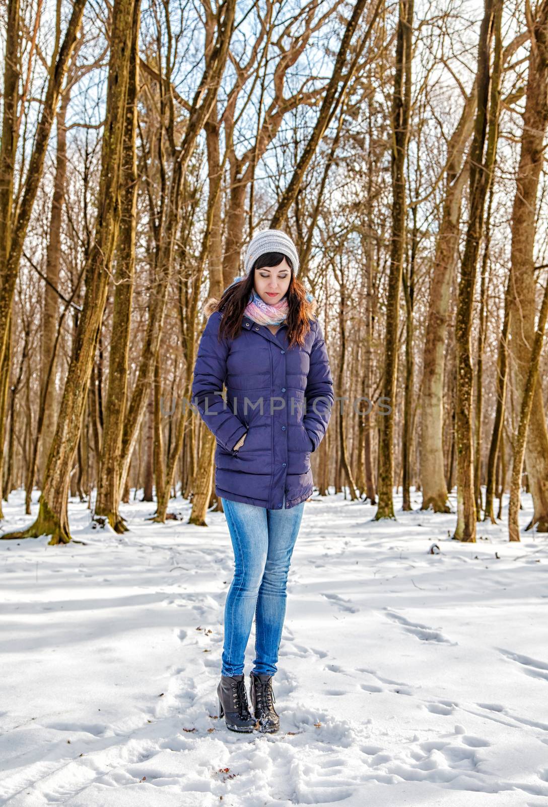 young beautiful woman walking in the woods in winter on sunny day