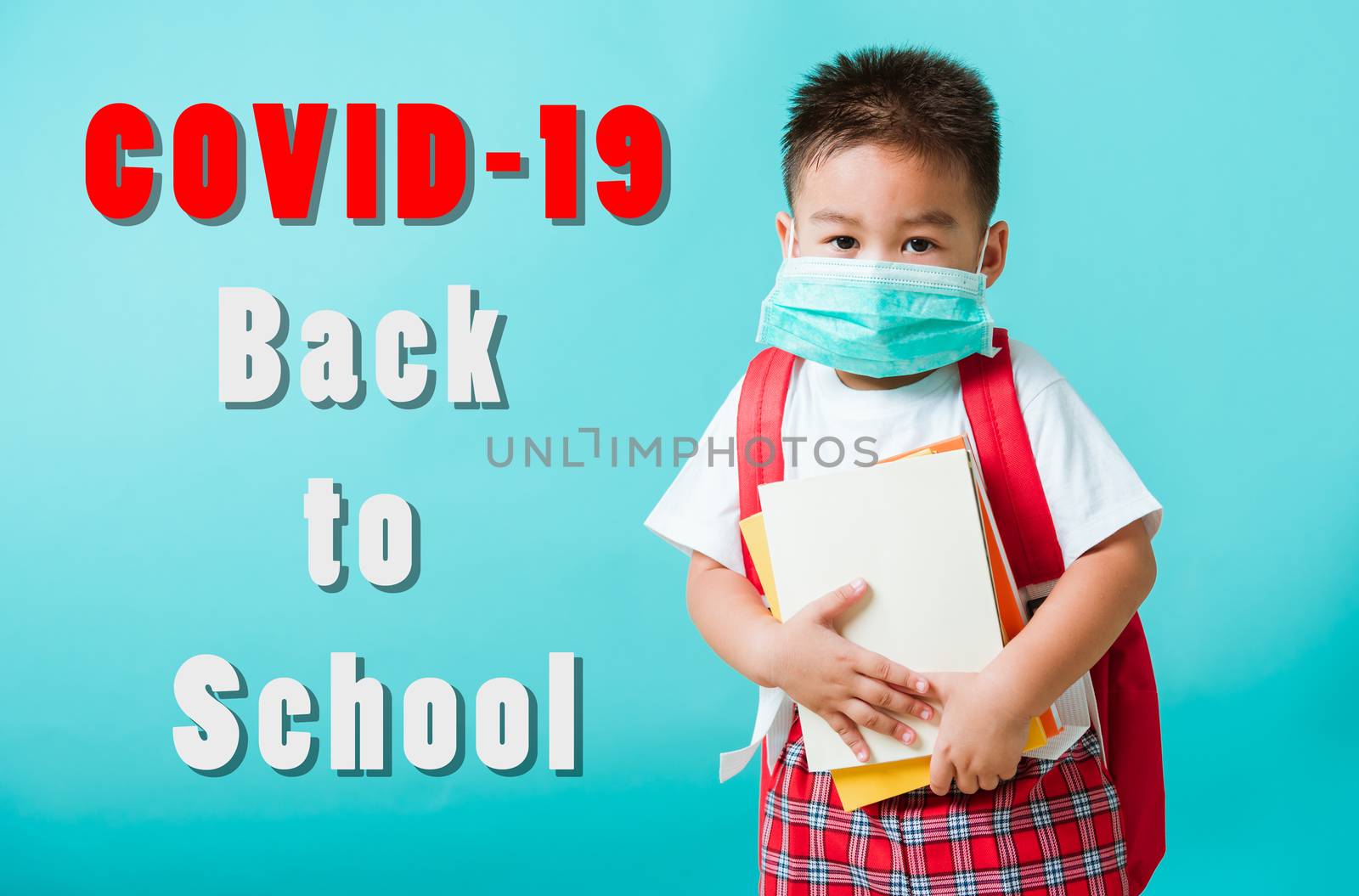 Back to school coronavirus Covid-19 education. Portrait Asian little child boy kindergarten wear face mask protective and school bag hold book before going to school, studio shot isolated background