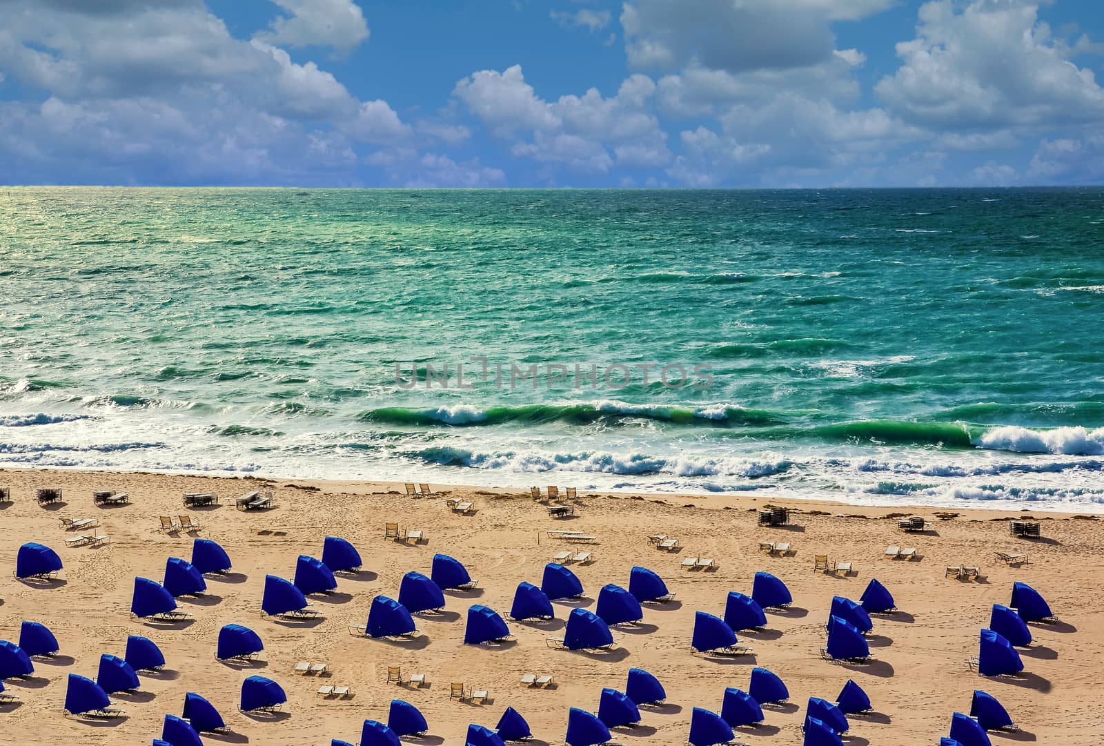 Lines of blue beach shelters by a stormy sea