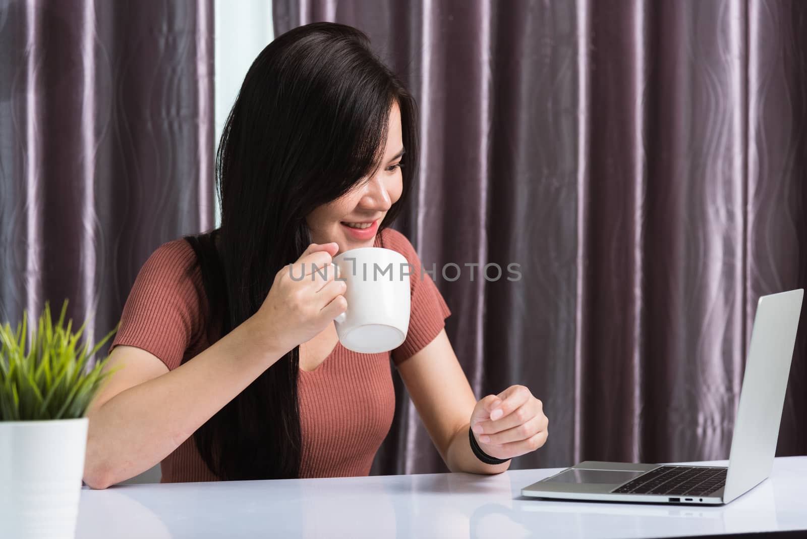 Work from home, Smiling Happy Asian business young beautiful woman sitting on desk workspace video call conferencing with team by webcam laptop computer technology at home office