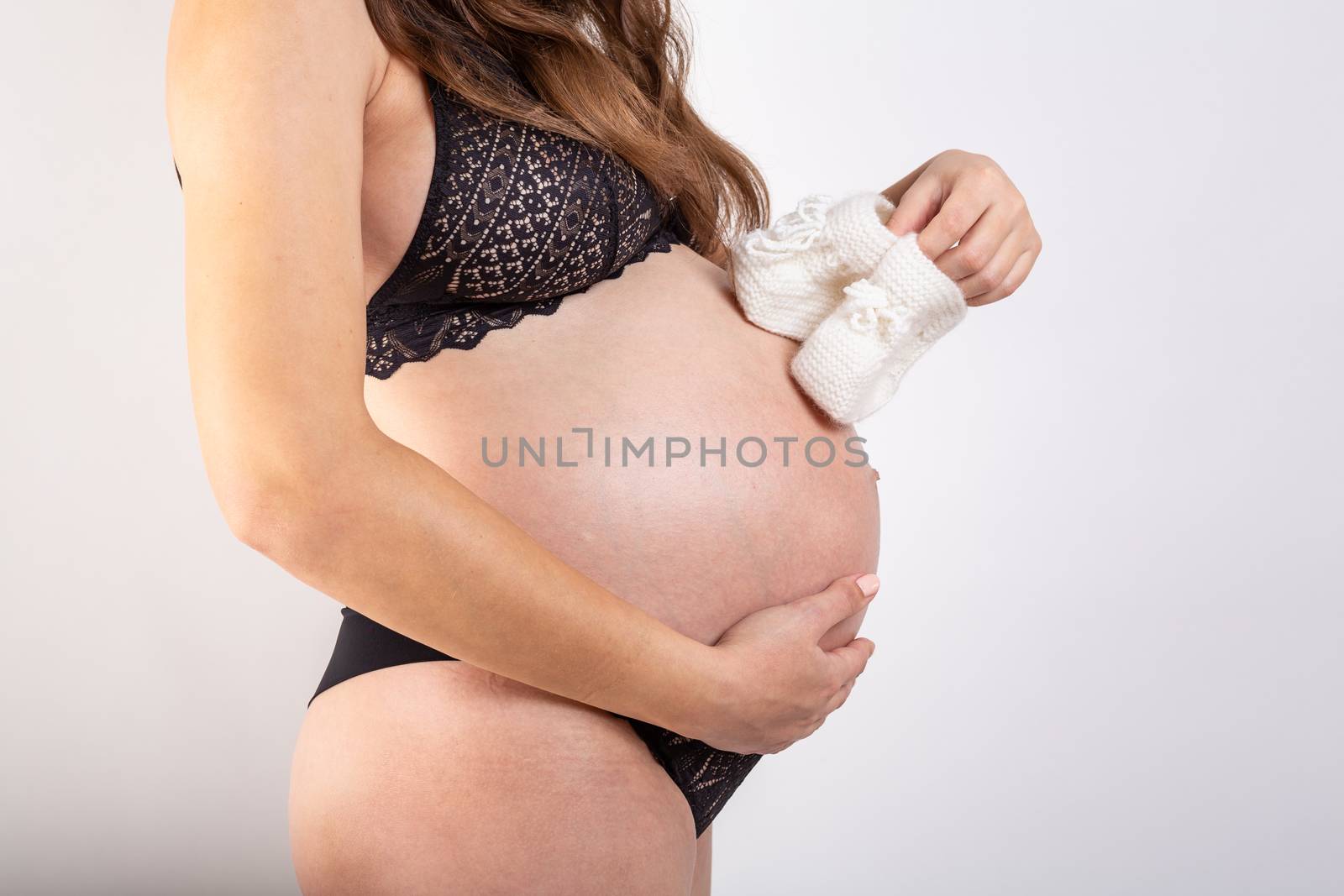 Pregnant Happy Woman holding blue Baby Shoes in her Hands. Mom Expecting Baby. Pregnant Woman Belly. Pregnancy by Vassiliy