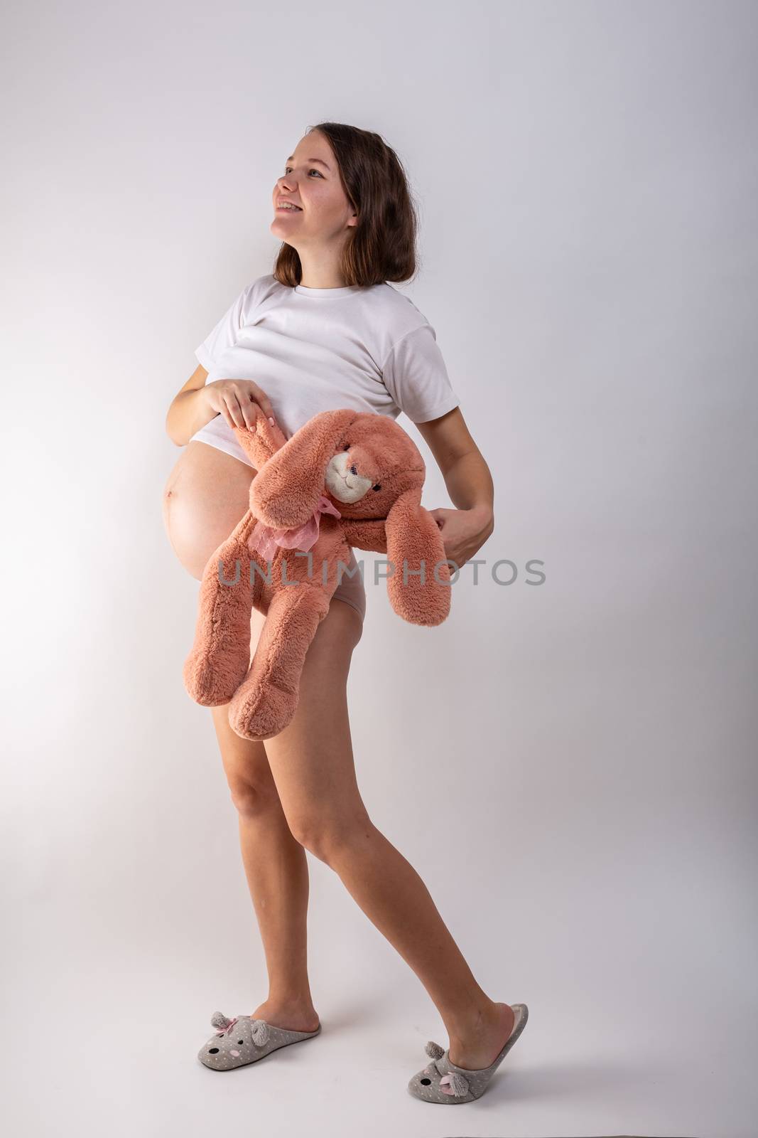 Close-up pregnant woman's belly with Hare toy. Beautiful pregnant woman. Pregnancy, parenthood, preparation and expectation concept