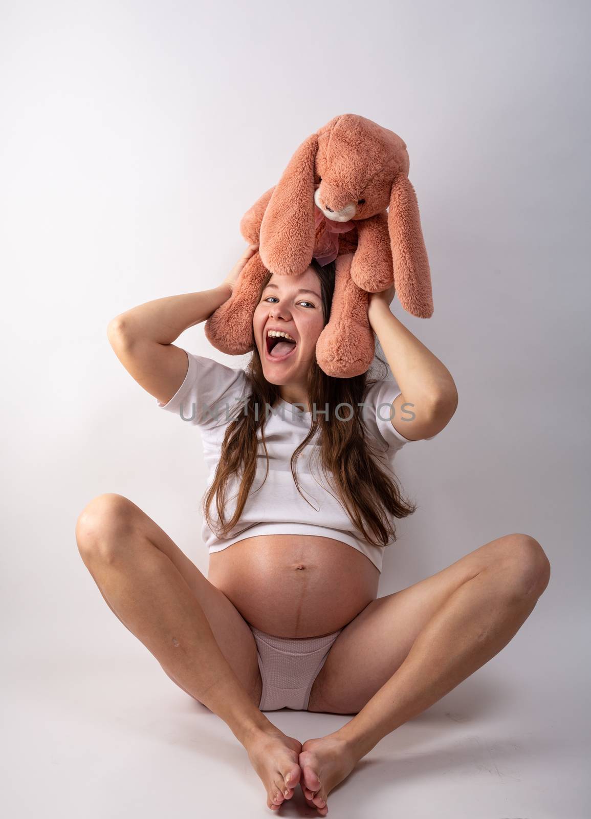 Close-up pregnant woman's belly with Hare toy. Beautiful pregnant woman. Pregnancy, parenthood, preparation and expectation concept