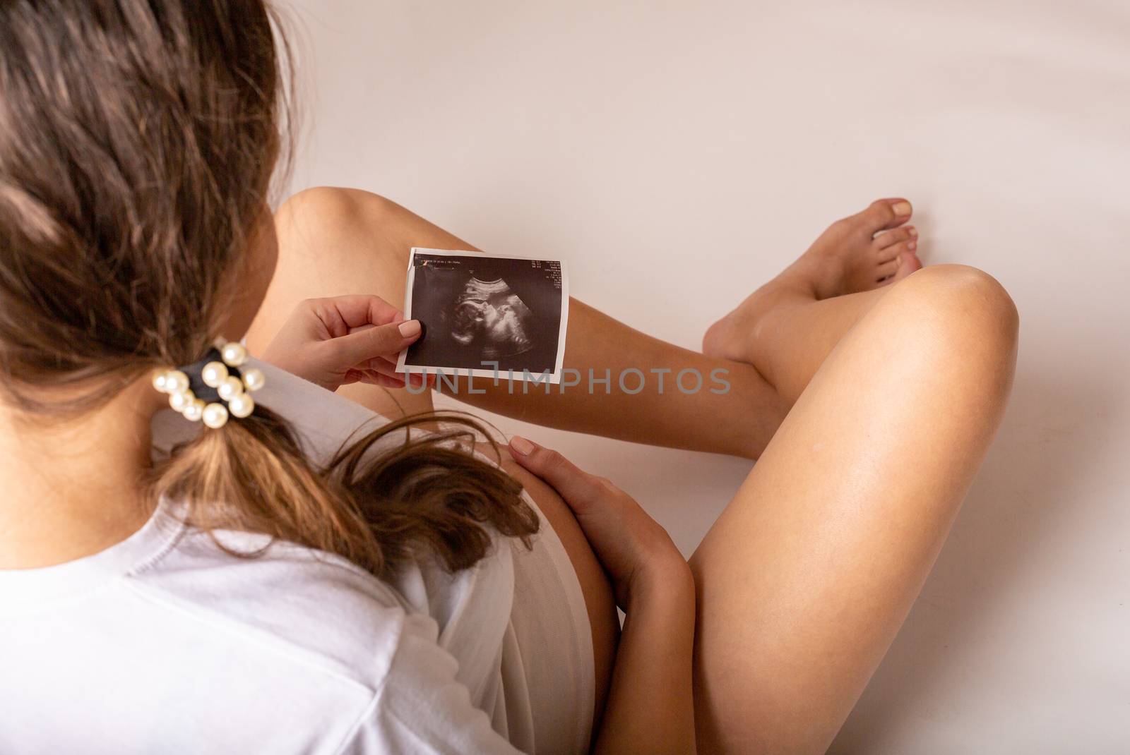 Pregnant woman looks at ultrasound photo.