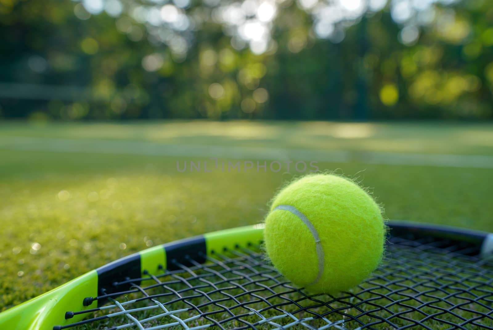 Tennis ball and racket in the artificial grass tennis court.