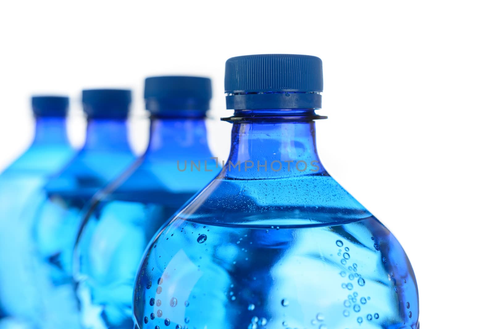 Fresh mineral water concept - cool bottles of mineral water in a row on a white background in close-up.