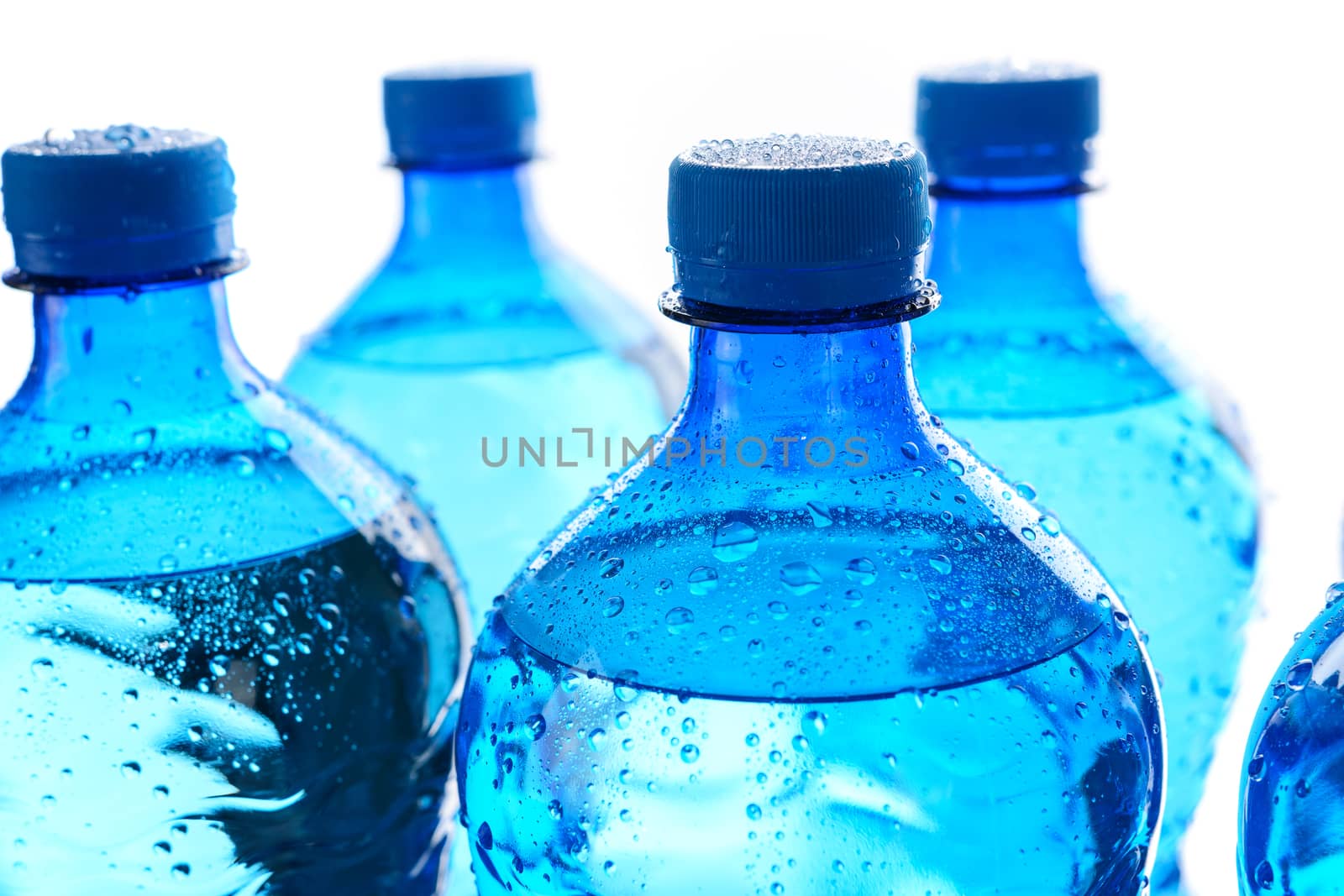 Fresh mineral water concept - cool and wet bottles with mineral water on a white background in close-up.