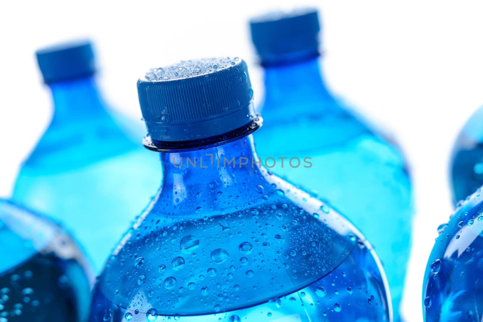 Fresh mineral water concept - cool and wet bottles with mineral water on a white background in close-up