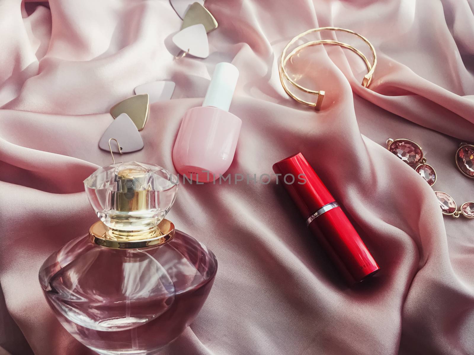 Fashionable and stylish accessories, jewelry and make-up products on pink silk background, beauty and fashion concept