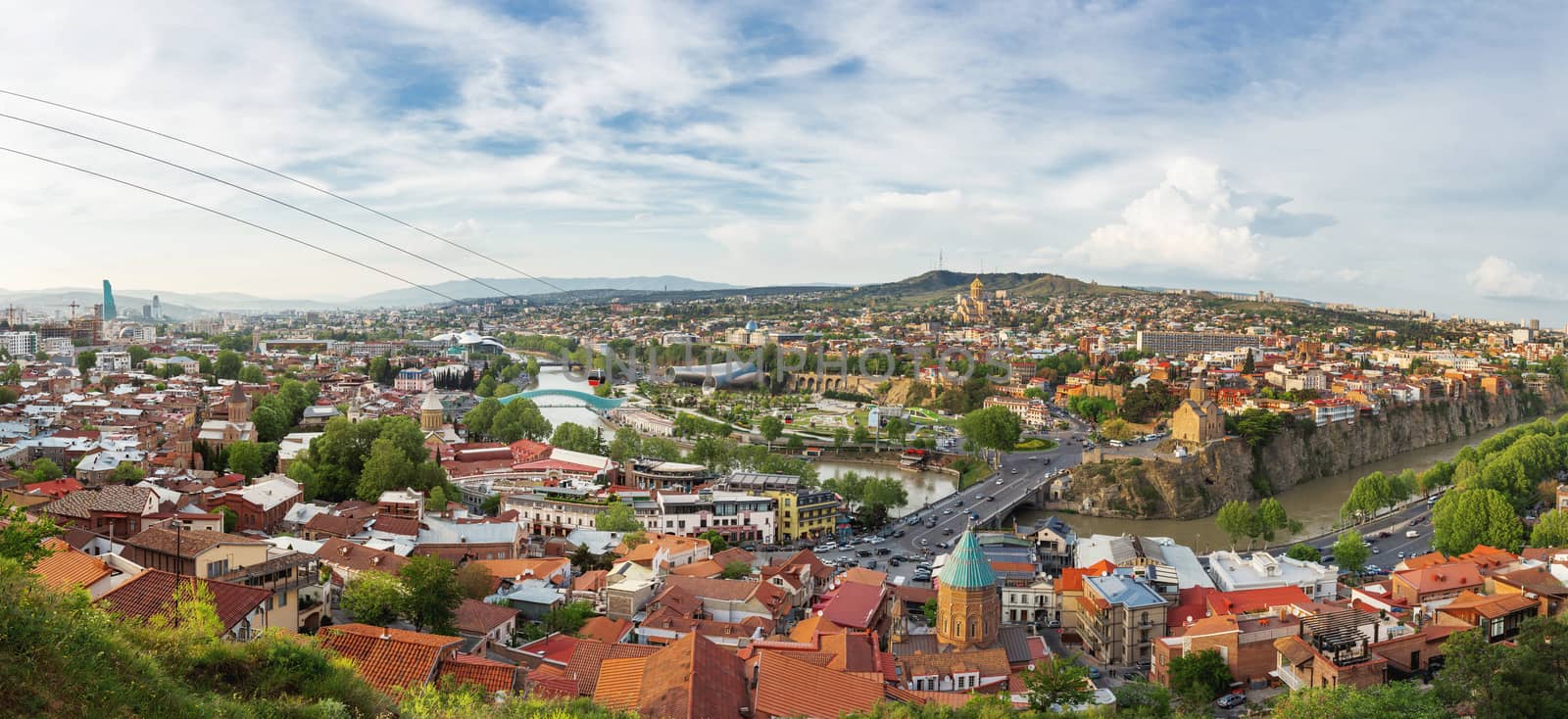 Large panorama view of Tbilisi, capital of Georgia country. View from Narikala fortress. Cable road above tiled roofs. by aksenovko