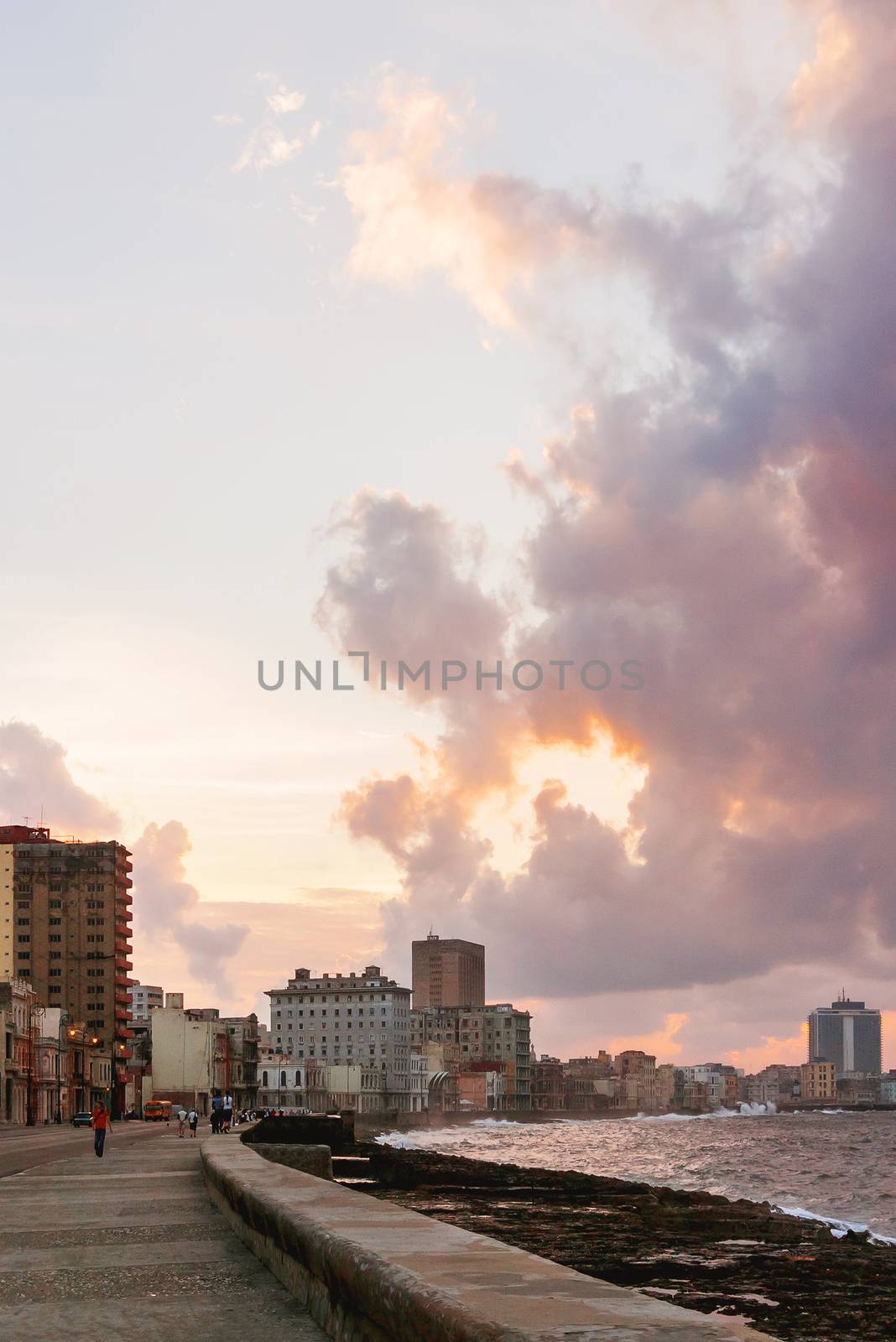 Famous embankment promenade Malecon at sunset. People walkind down the street. Havana, Cuba. by aksenovko