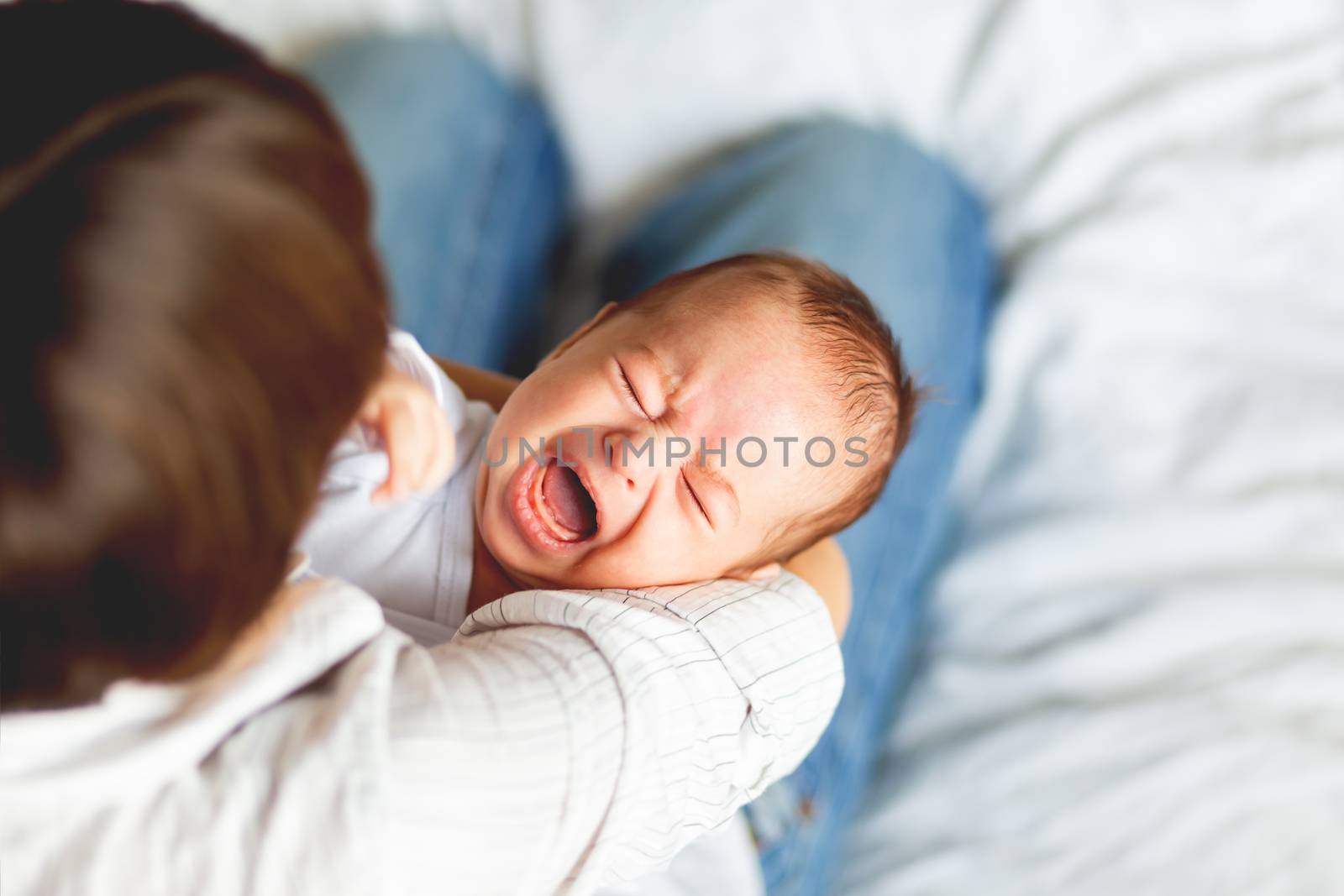 Woman holding a crying child. Mother comforts her little son or daughter.